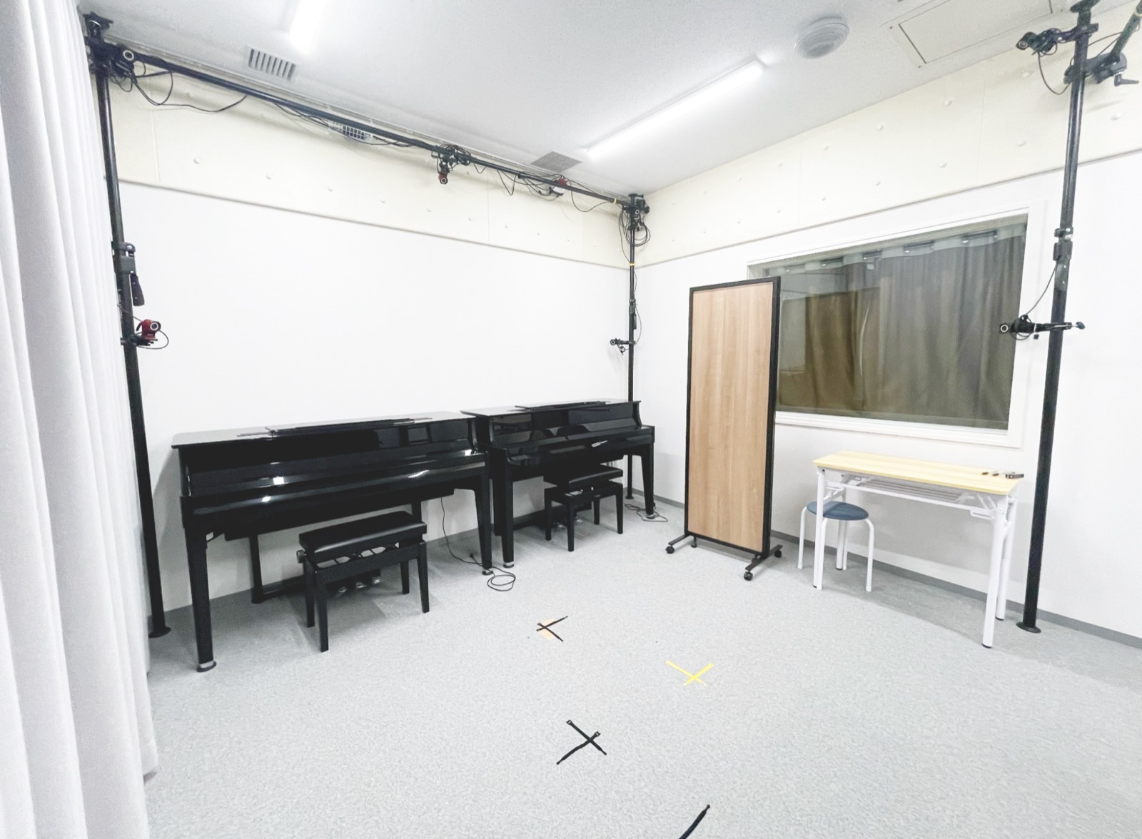 演奏科学実験室。2台のピアノとモーションキャプチャカメラを取り付けた支柱、観察窓が見える。